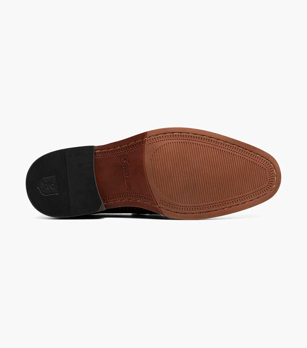 The Stacy Adams Madsen Moc Toe Bit Slip On in brown features a textured leather upper, metal bit detail, anatomical arch support, and RedZone footbed for comfort, all set on a low heel and shown against a white background.