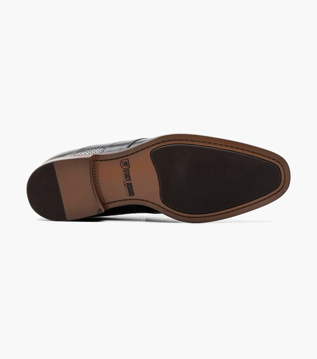 The STACY ADAMS Karnes Moc Toe Penny Slip On in black (25591-001) features an orthotic insole with a molded heel cup, anatomical arch support, cushioned heel pod, and durable rubber outsole. Displayed on a white background with labeled features.