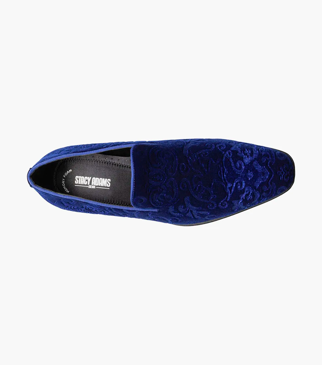 The STACY ADAMS Saunders Debossed Velour Slip On in Royal features a blue velour upper, low heel, intricate swirl embroidery, and a memory foam footbed. Shown in side profile against a white background. Style number: 25581-432.