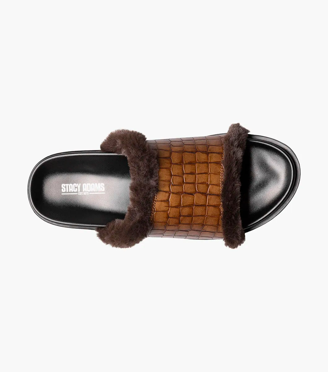 The STACY ADAMS Monty Slide Sandal in Cognac features a brown crocodile print leather strap, dark brown faux fur trim, and black sole, shown on a white background. Style number: 25560-221.