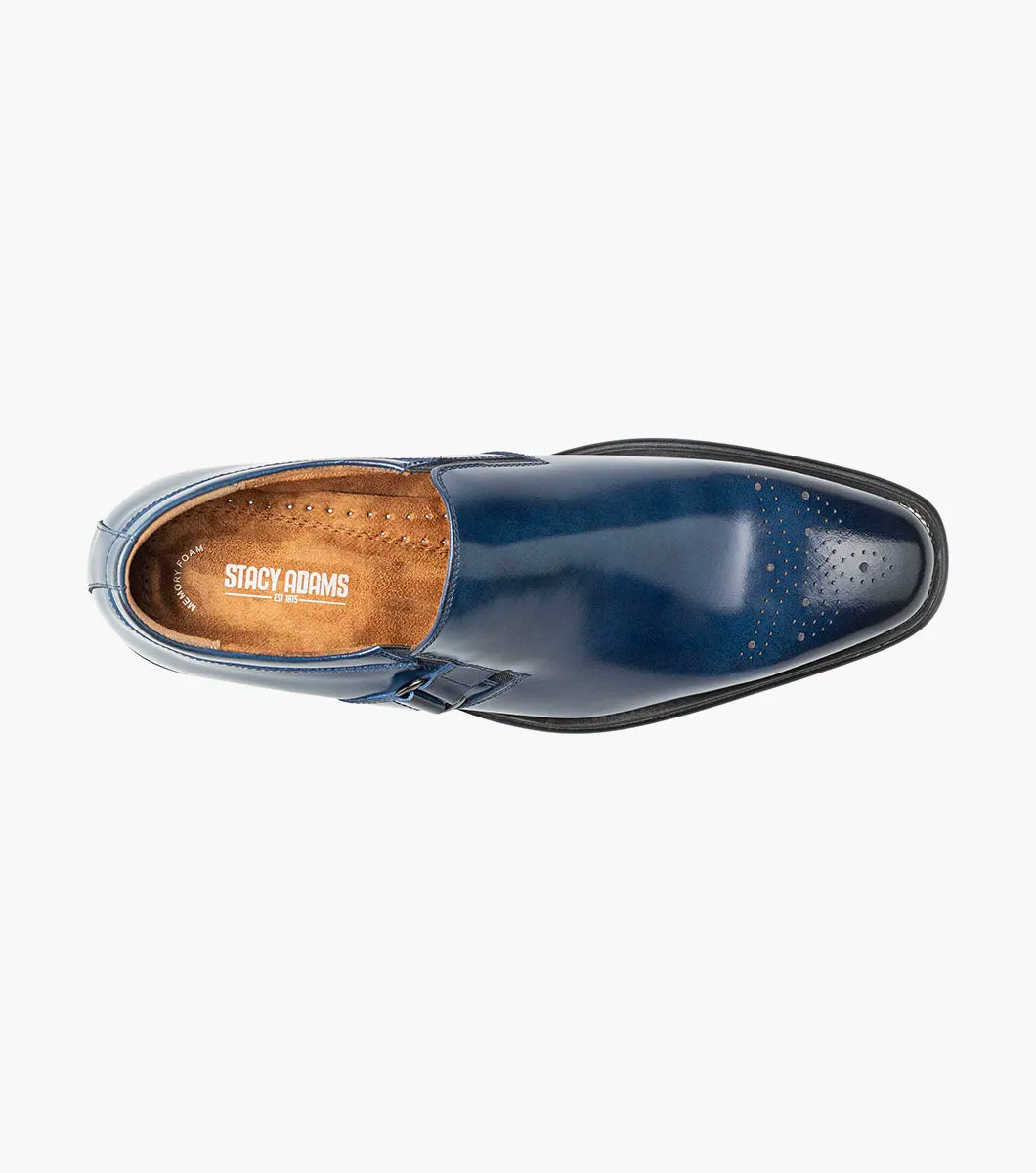 The Stacy Adams Alistair Plain Toe Ornament Slip On in cobalt (style 25792-435) is a single blue calf leather slip-on dress shoe featuring a low heel, decorative perforations on the toe, a side buckle detail, and a comfortable memory foam insole, shown on a white background.
