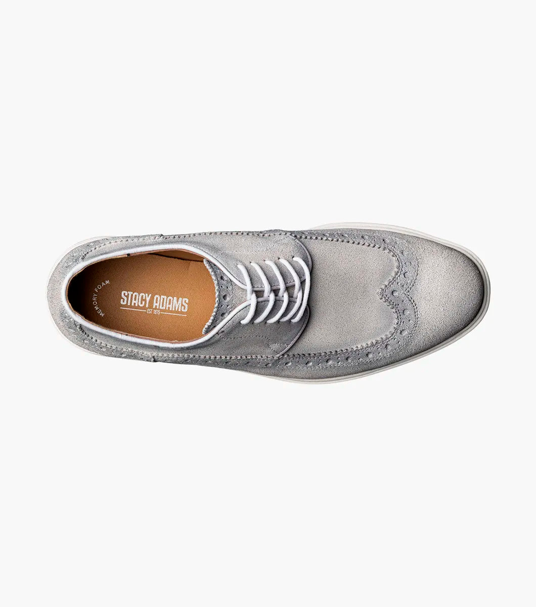 The STACY ADAMS Trudell Wingtip Lace Up in Light Gray (25691-050) features gray suede leather, white laces, and a white rubber sole, shown in a side profile against a plain background.