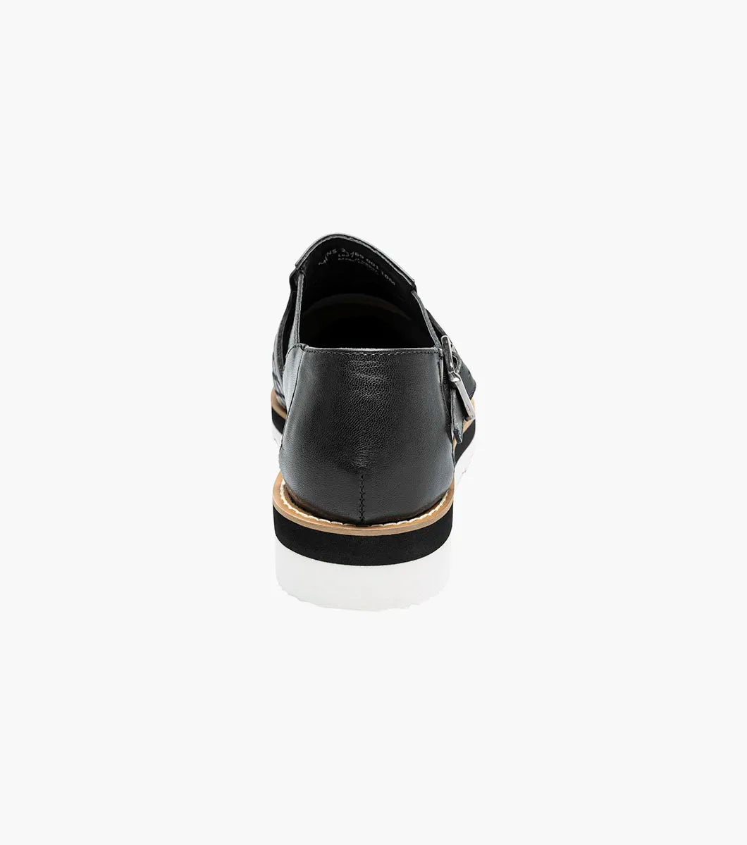 The Stacy Adams Alvarado Woven City Sandal features a black woven leather upper, buckle strap, closed toe, memory foam insole, and a white ridged sole with tan accent.