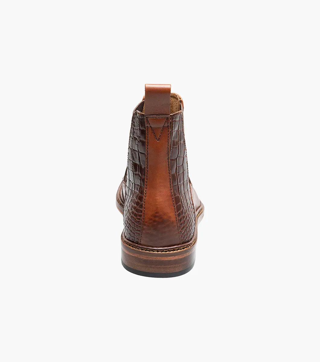 The Stacy Adams Garza Wingtip Chelsea Boot in Cognac features crocodile texture detail, elastic side panel, heel pull tab, cushioned footbed for comfort, and a low wooden sole.