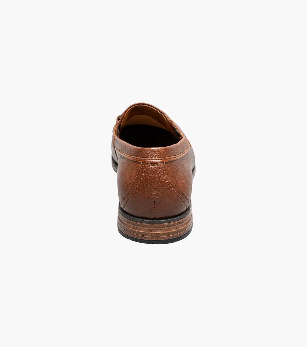 The STACY ADAMS Richmont Moc Toe Bit Slip On in Cognac Tumbled (21567-222) is a brown leather loafer with a metal bit, moc toe slip-on design, low wooden heel, and detailed toe stitching, shown on a white background.