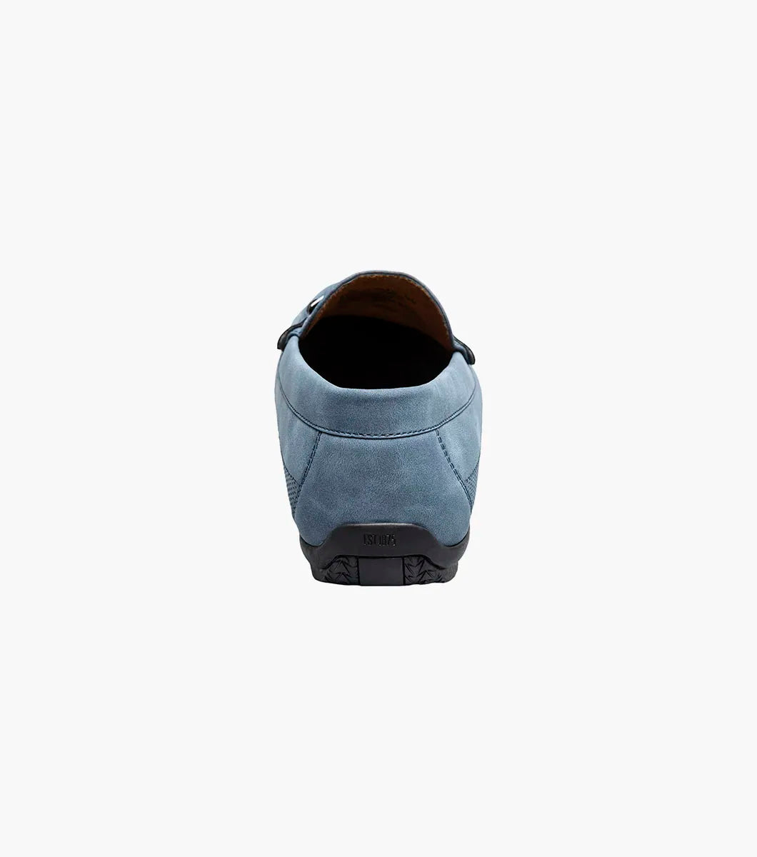 The STACY ADAMS Colton Moc Toe Bit Slip On (Navy, 25760-410) features a cushioned footbed, metal bit detail, moc toe stitching, and a flat black sole, shown on a white background.