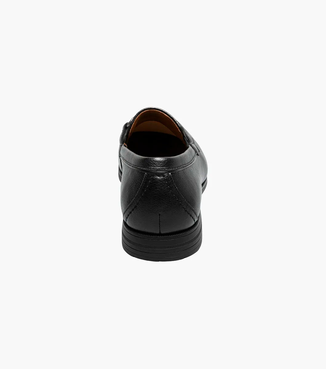 The STACY ADAMS Richmont Moc Toe Bit Slip On in Black Tumbled (21567-007) features black leather, a metal bit detail, low heel, and brown lining—shown here as a stylish dress casual loafer on a white background.