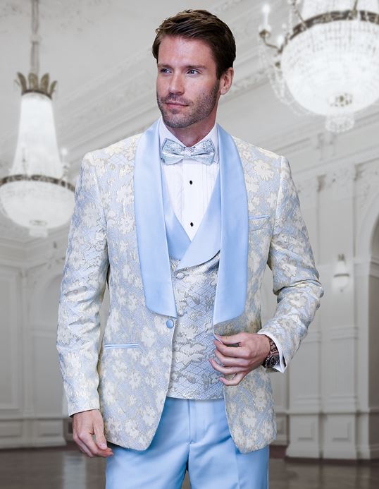 A man in a STATEMENT TIZANO SKY BLUE Suit from Statement Clothing with a bow tie stands in an ornate room with chandeliers.