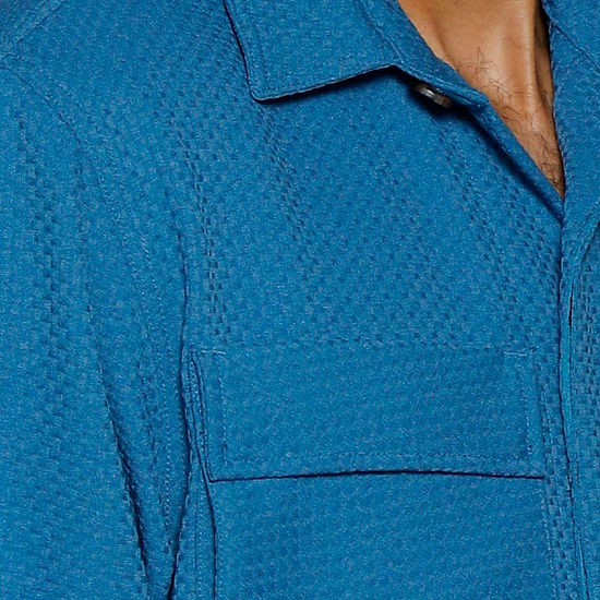 A man wearing the Insomnia INSOMNIA ROBERTO 2PC Teal Leisure Suit stands in front of an ornate white wall.