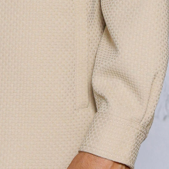 A man stands indoors in the INSOMNIA ROBERTO 2PC Tan Leisure Suit by Insomnia, featuring a textured button-up shirt with two large chest pockets and matching pants for a relaxed, casual look.