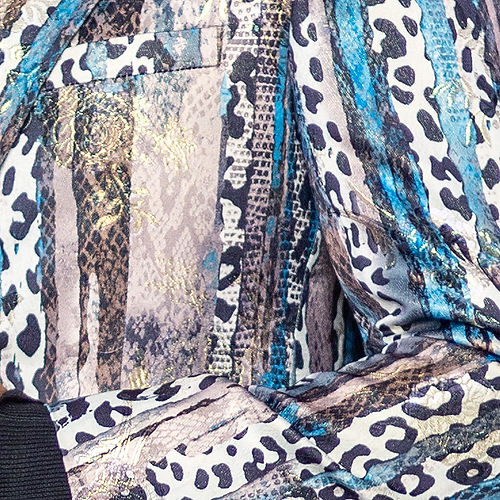 A man wearing a Manzini MANZINI MZS-559 Men's Tailored-Fit Leopard/Reptile Sport Coat Jacket Blazer Blue, a black turtleneck, and blue jeans stands in front of a black curtain.