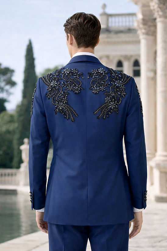 A young man wears the Manzini GQ300 2-Piece Slim-Fit Men's Rhinestone Pattern Double Breast Tuxedo Suit in navy, posing outdoors beside a woman in a blue dress with a thigh-high slit near classical architecture.