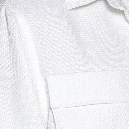 A man stands against a light-paneled wall wearing the INSOMNIA CAVALLI 2PC White Leisure Suit by Insomnia, featuring two large chest pockets and matching white pants—a refined take on casual attire.