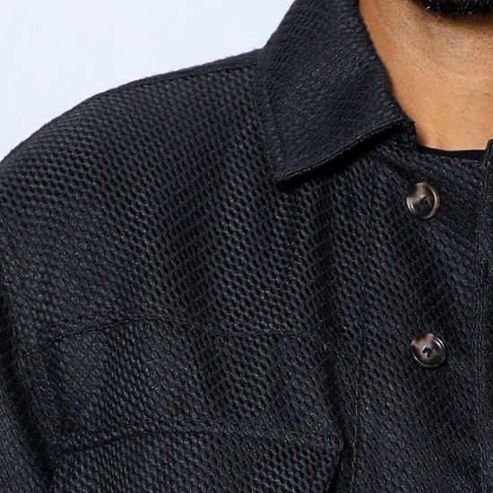 A man stands against a light-colored, paneled wall wearing the Insomnia INSOMNIA FENDI 2PC Black Leisure Suit.