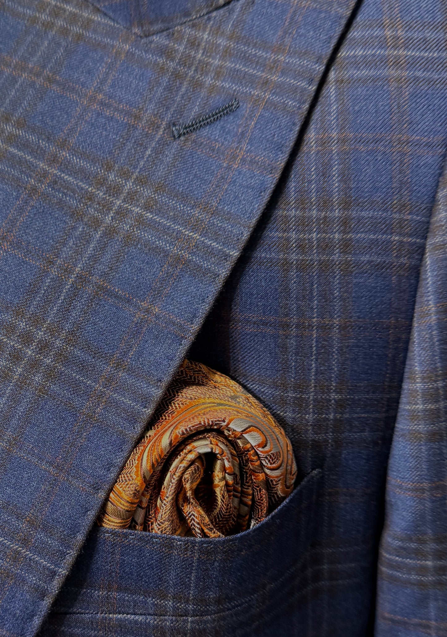 A man wearing a Tiglio Rosso Orvietto Blue with Brown Plaid and Rust Windowpane TL8101A semi wide leg suit stands against a plain white background.