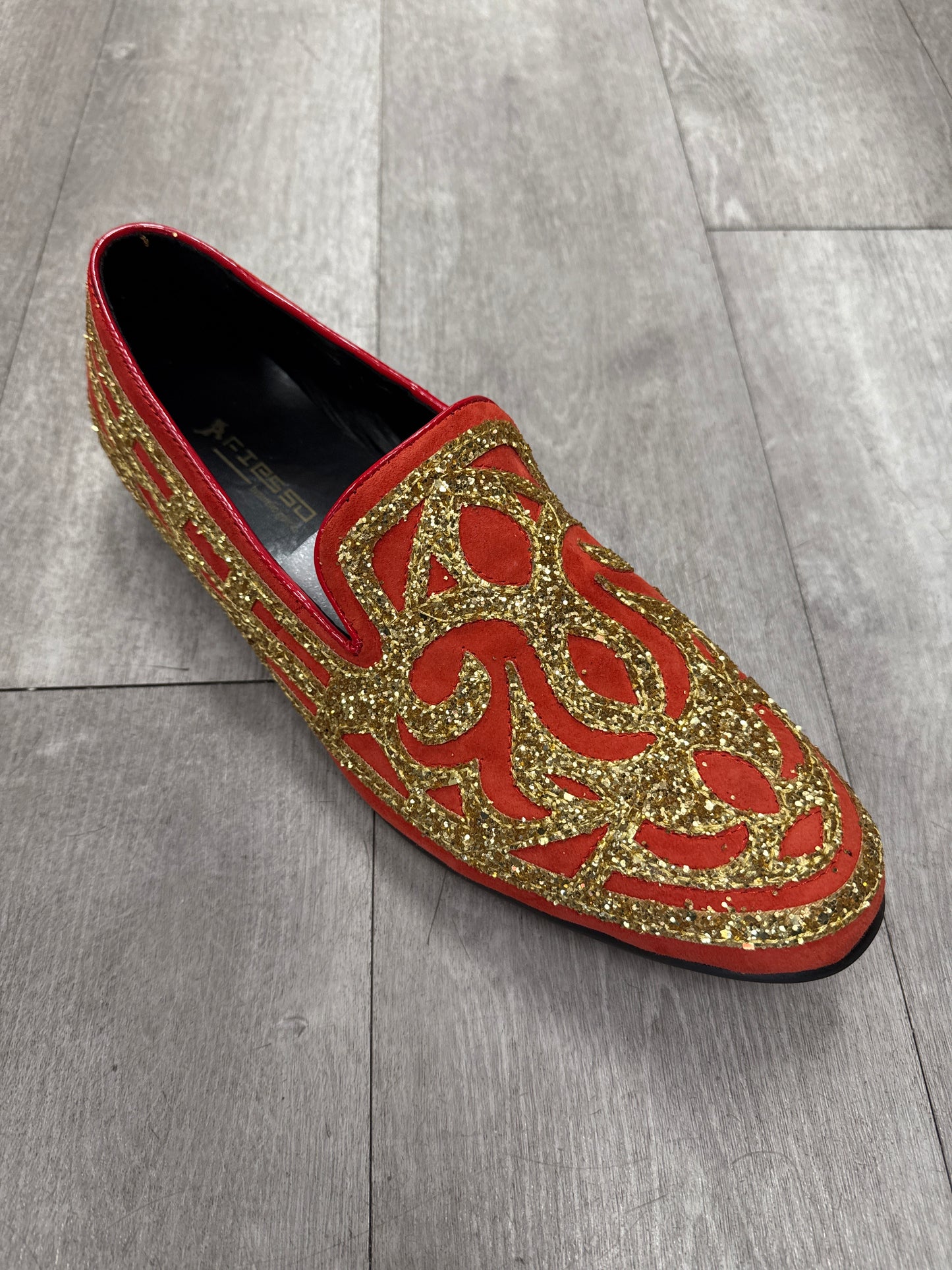 Fiesso Shoe 99, size 9 only—red slip-on dress shoe with gold glitter patterns on a gray wooden floor. FINAL SALE: no exchange or return.