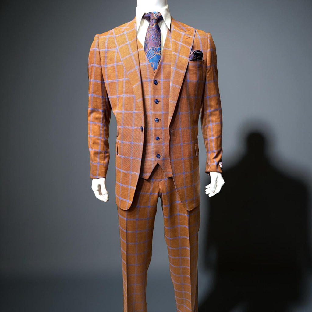A man wears the Tiglio Rosso ORVIETTO Rust Blue Windowpane Semi Wide Leg TL8067 suit with a white shirt, patterned tie, and pocket square, standing forward against a plain white background to showcase its semi wide leg fit.