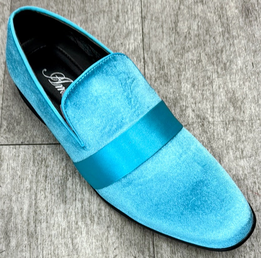 The Exclusive Formal Dress Shoe Teal 7021 from UNIQUE DESIGN MENSWEAR, a single turquoise men's loafer made from genuine leather featuring a shiny band across the top, is elegantly placed on a light grey wooden floor.