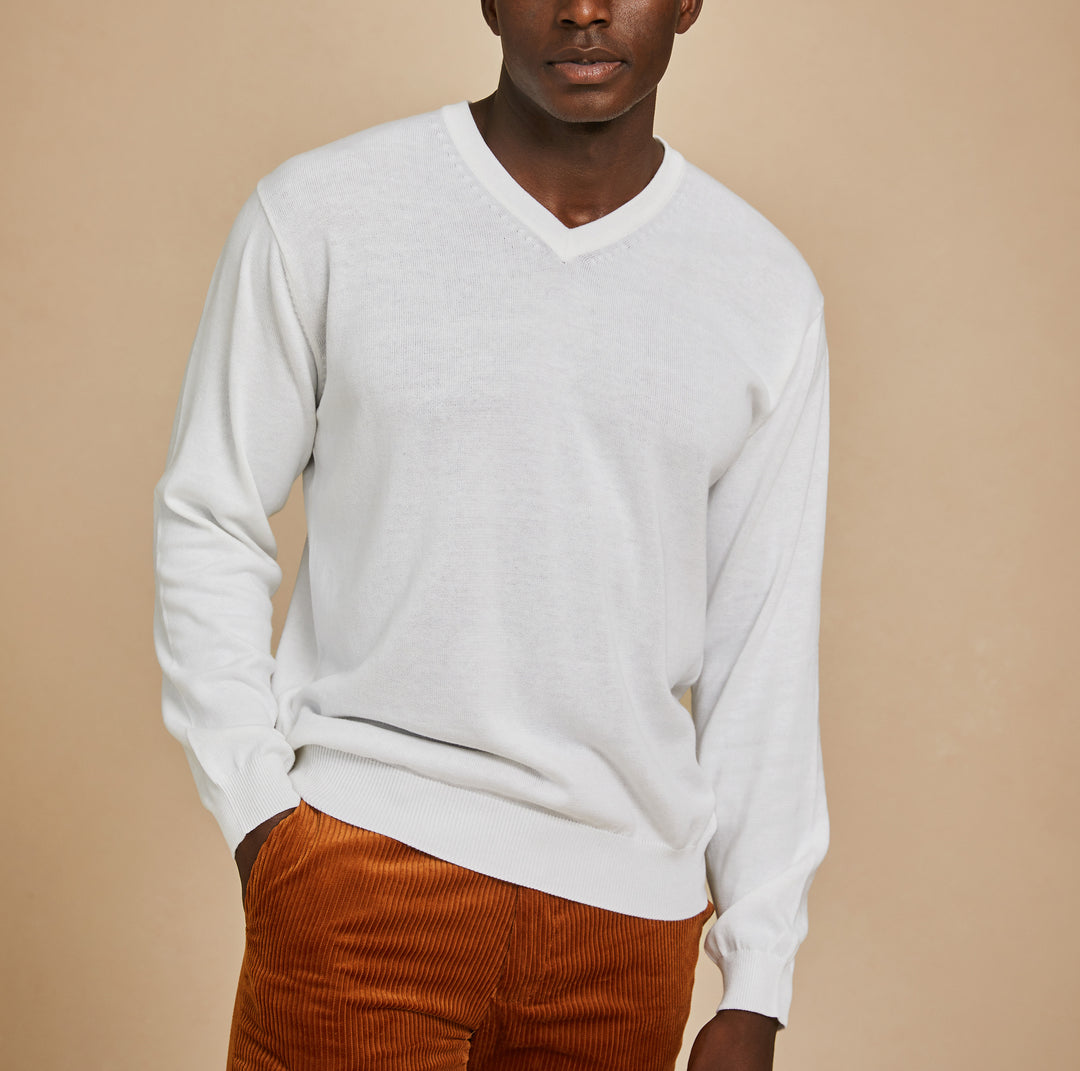 A man wears the Inserch Cotton Blend V-Neck Sweater 4608-00002 in white and rust corduroy pants, standing against a plain beige background.