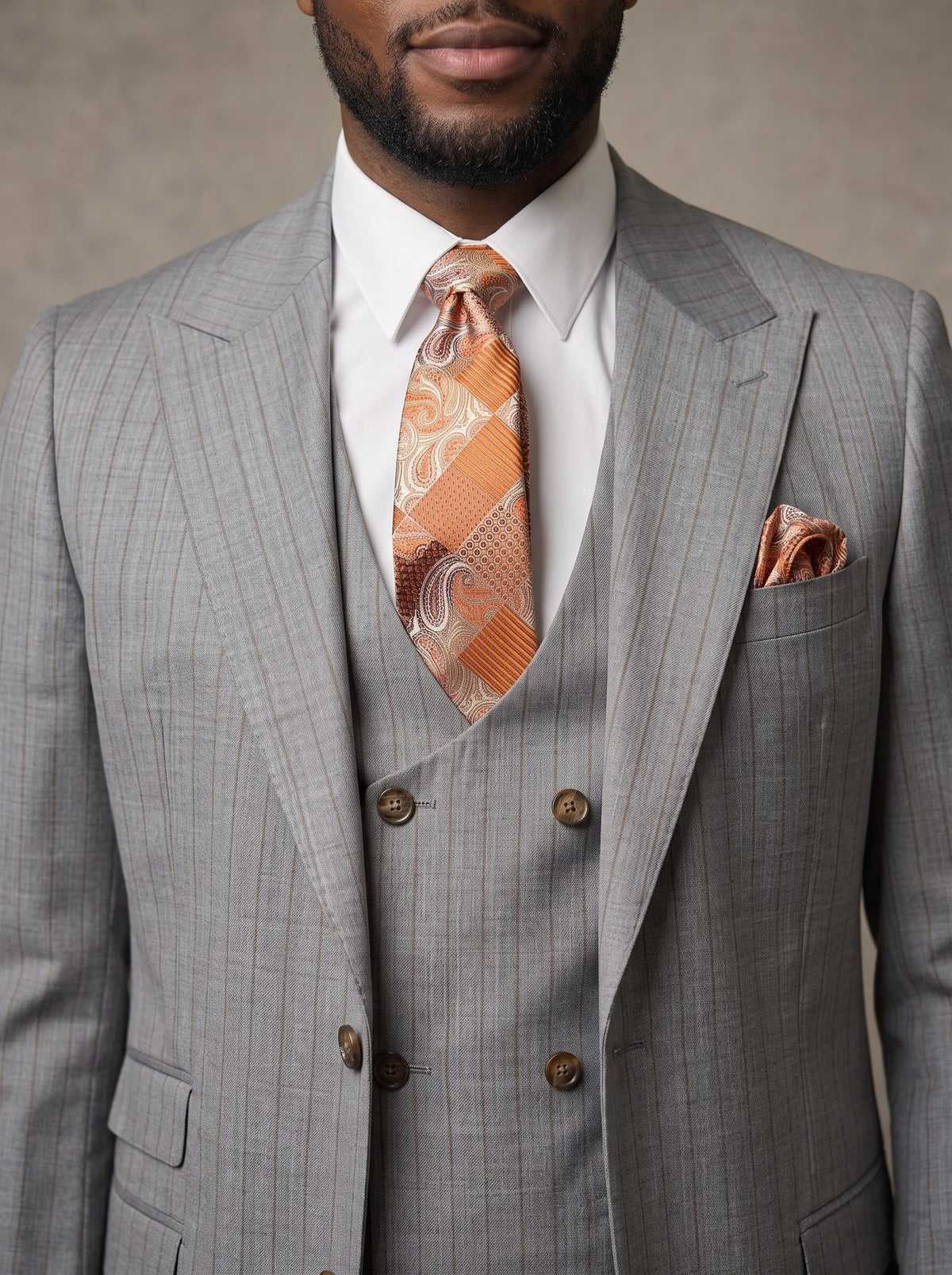 A man wears a Tiglio Luxe Prosecco, Modern Fit Pure Wool Grey/Rust Stripe Suit & Vest TL9111, featuring a grey striped three-piece wool suit, white shirt, rust-colored patterned tie, and pocket square.