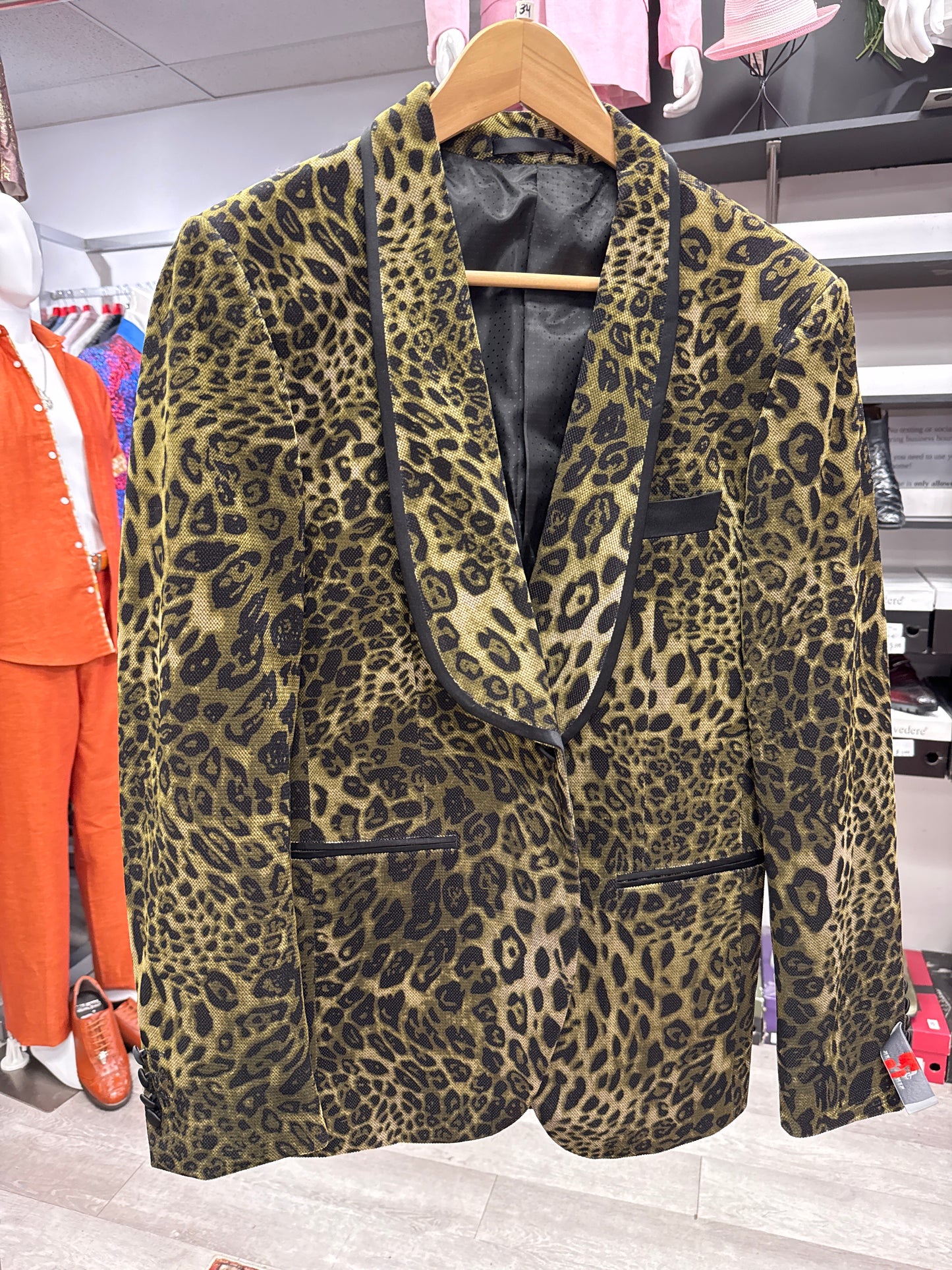 The EJ SAMUEL JACKET 14 CLEARANCE, a leopard print blazer with black trim, is displayed on a wooden hanger in a clothing store. Final sale—no exchanges or returns.
