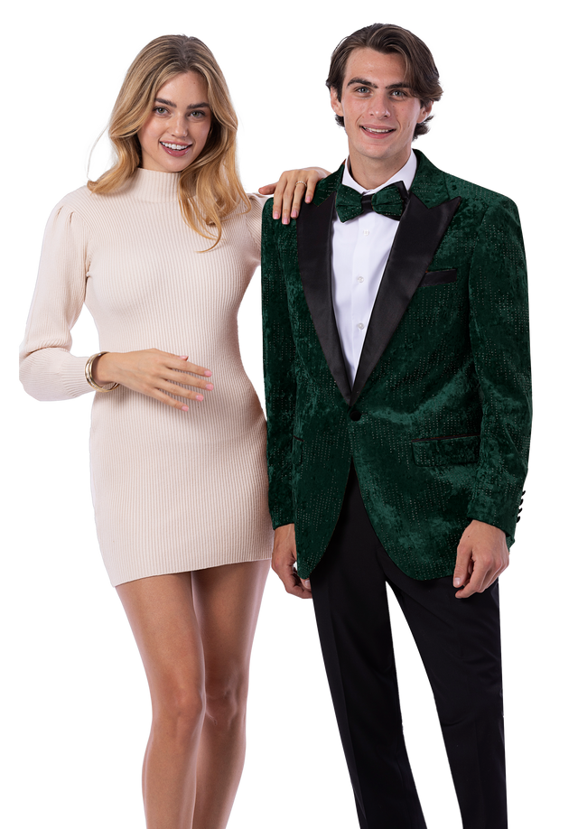 A woman in a light beige long-sleeve dress stands next to a man wearing the EJ SAMUEL Hunter Blazer J207—a green velvet blazer paired with a white shirt, black bow tie, and black pants. Both are smiling at the camera.