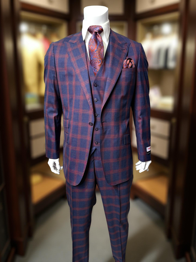 A man stands against a plain background wearing a Tiglio Rosso Portofino Semi Wide Leg TL8066 suit, white shirt, paisley tie, and pocket square.
