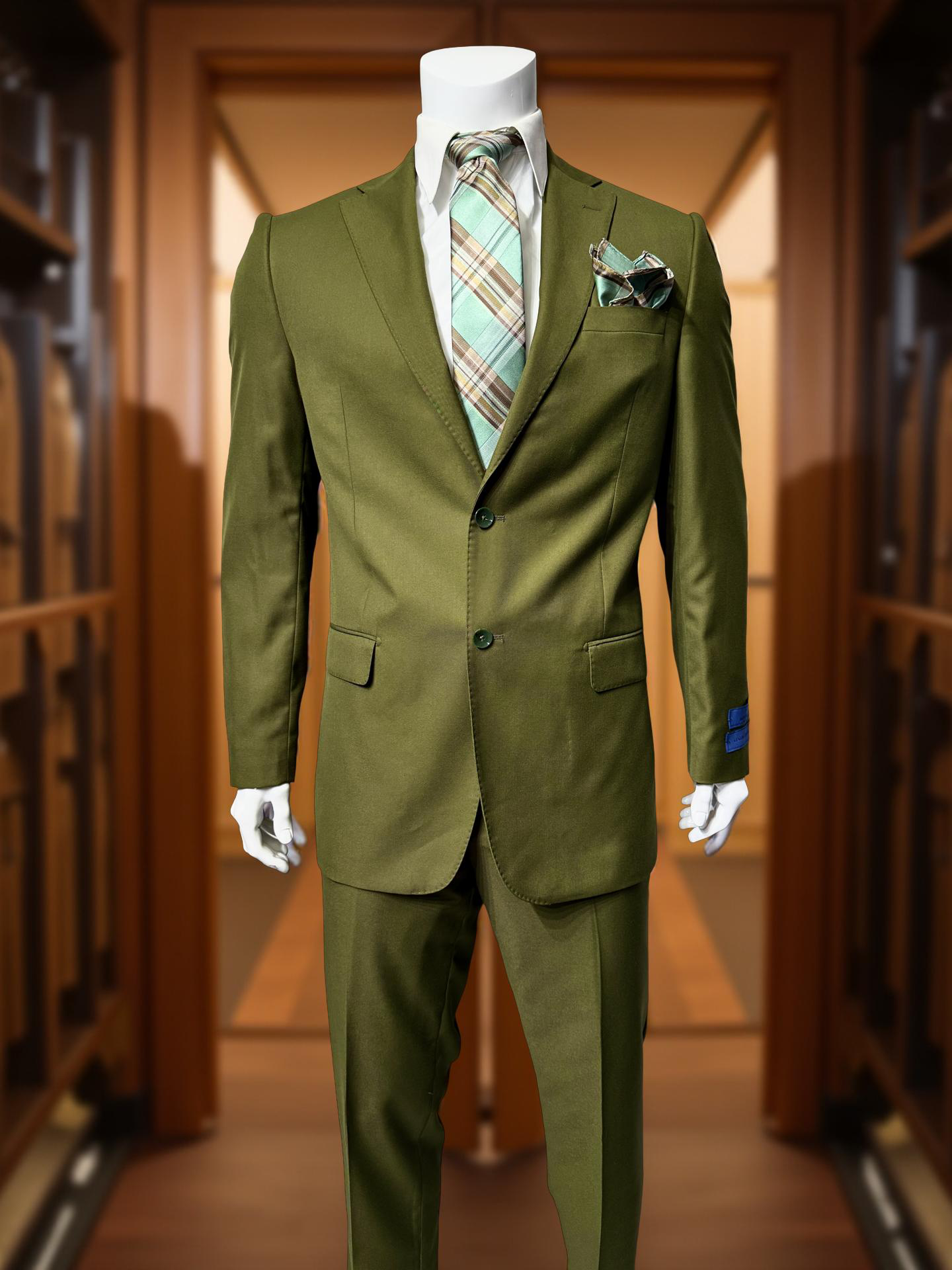 The Cavellini Uomo Dolcetto MODERN FIT Suit 6667/112 by CAVELLI is displayed on a mannequin with matching trousers, a plaid tie, and pocket square in a wood-paneled room.