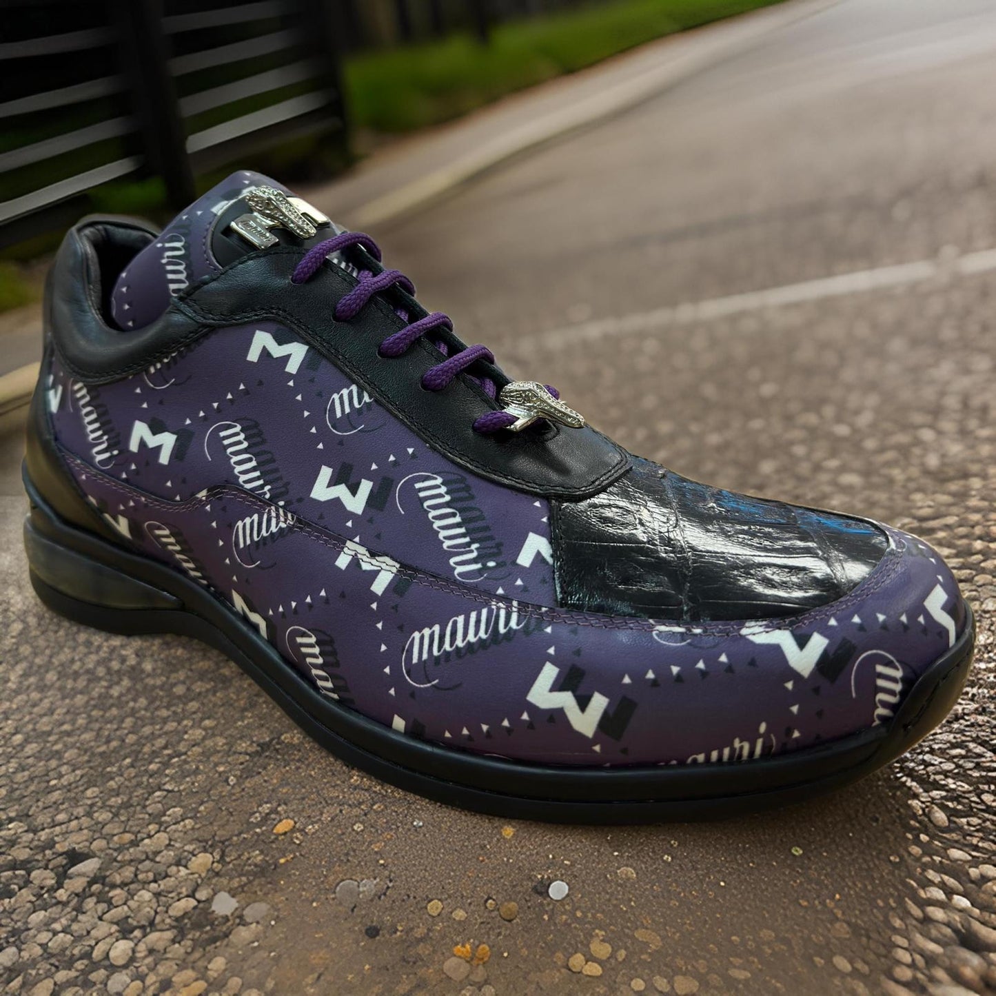 The Mauri 8900 Purple/Black shoes, in final sale and available in-store, boast a vibrant lettered pattern with a shiny patent leather toe cap, resting on a textured outdoor surface.