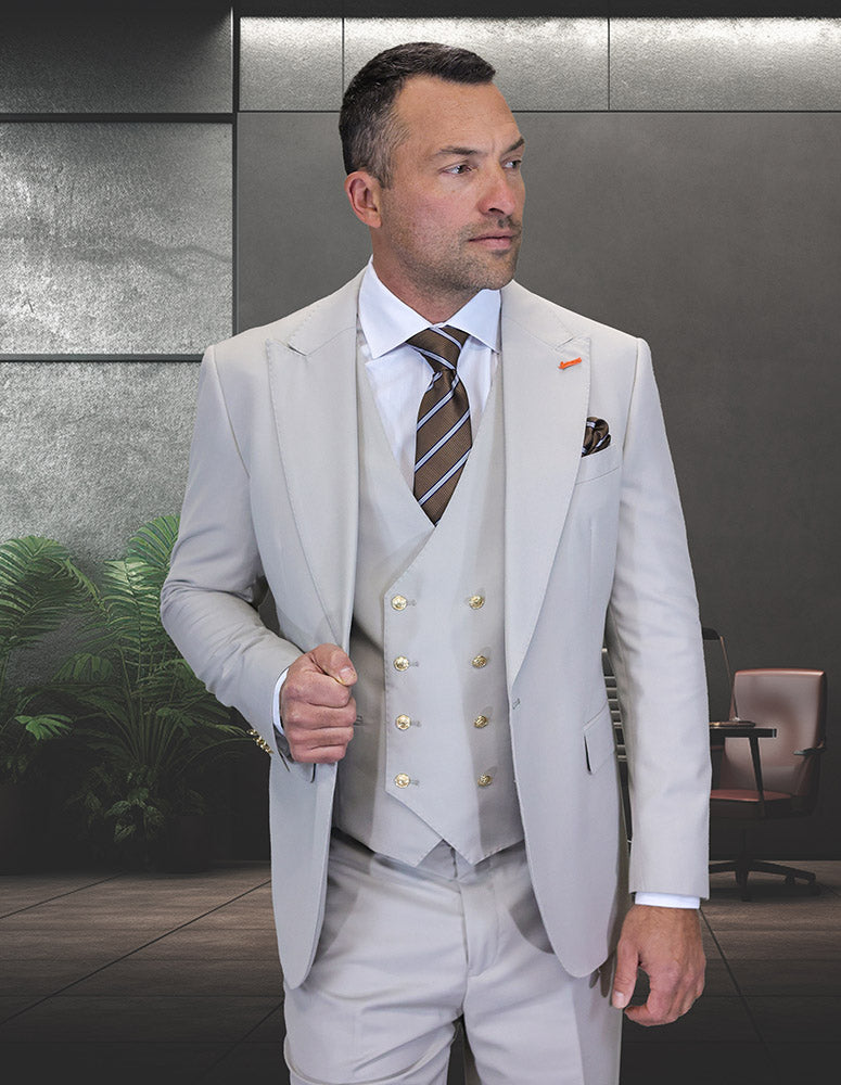 A man in the STATEMENT CLOTHING | AMIRI-ASH modern fit Italian wool three-piece light grey suit and striped tie stands in a modern office with plants and an office chair, representing Statement Clothing.