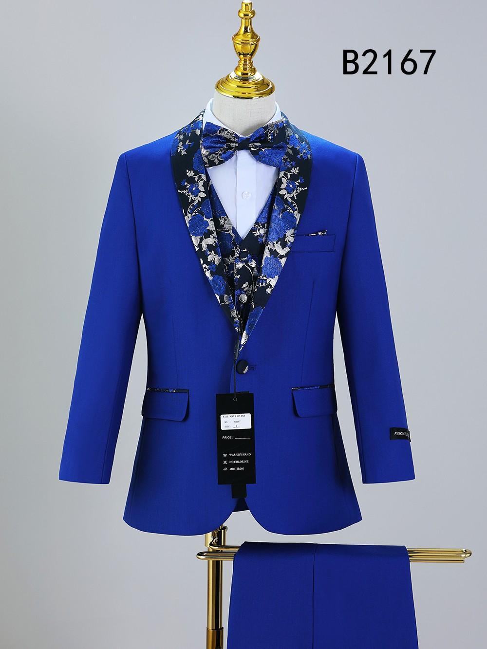 The BOY SUIT 5-PC SET B2167 by Unique Design Menswear features a bright blue suit with floral lapel, matching bow tie and vest. Displayed on a mannequin, it's perfect formal wear for boys at special occasions. Code "B2167" visible.