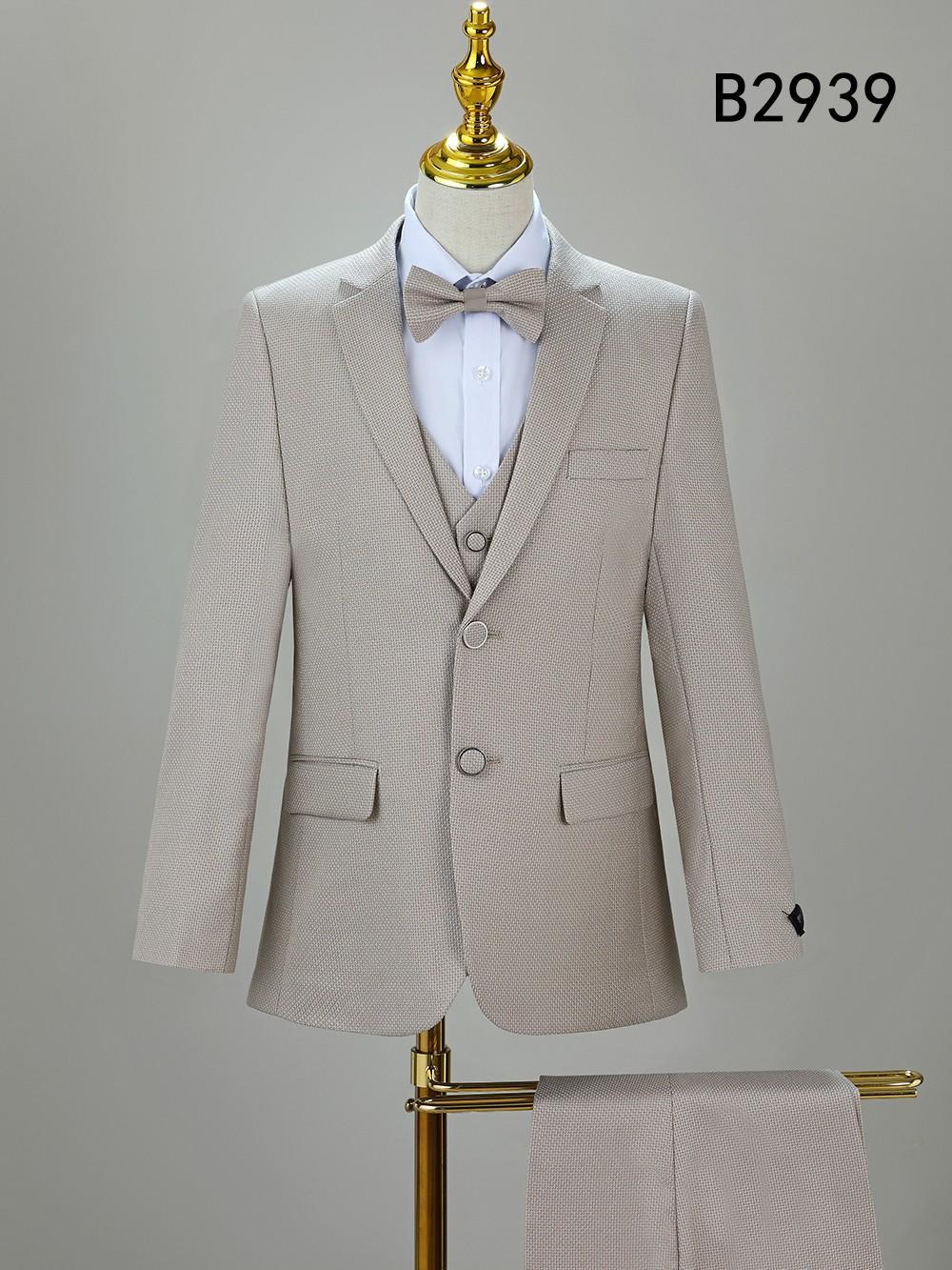 Unique Design Menswear’s BOY SUIT 5-PC SET B2939 in beige includes jacket, vest, white shirt, matching bow tie on mannequin, and trousers on a stand. Code "B2939" is shown in the corner.