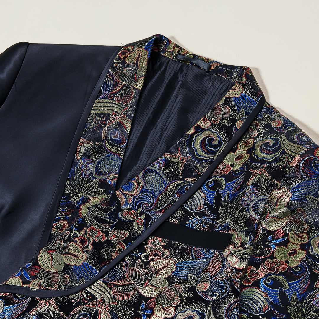 The Inserch Tied Floral Blazer BL207-01 Black by Inserch features a slim fit, with one side in solid black satin and the other in vibrant floral jacquard, finished with a sleek shawl collar and styled over a royal blue turtleneck.