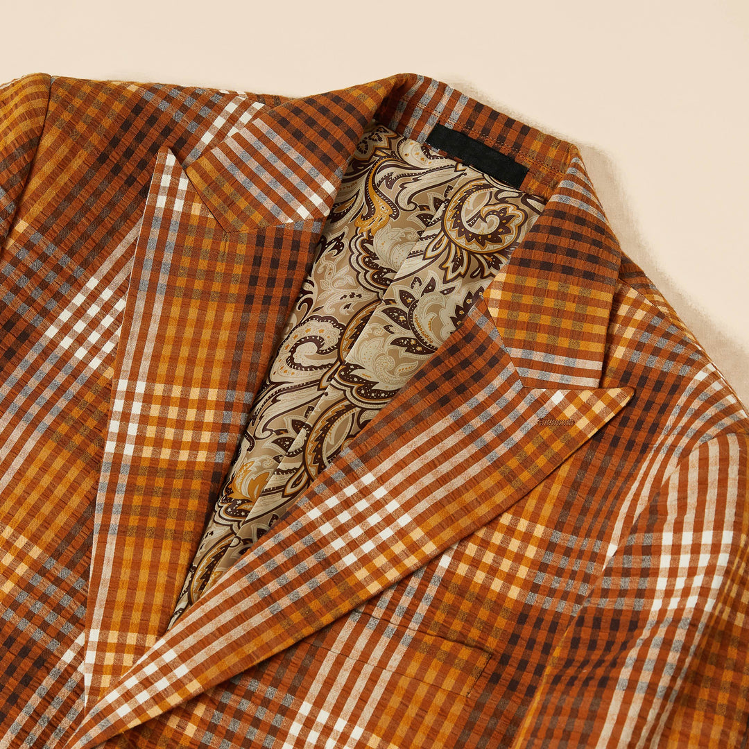 A model wearing the Inserch Seersucker Gingham Blazer BL272-00027 Aztec by Inserch and a white shirt stands against a plain beige background, with the blazer buttoned twice, highlighting its sleek design.