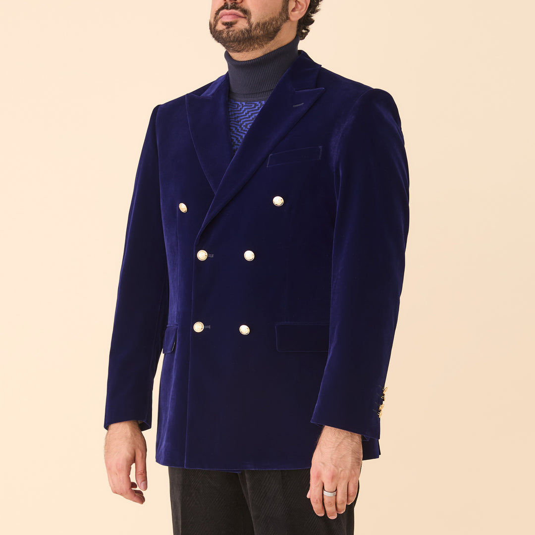 A man wears the Inserch DB Velvet Blazer BL502-13 Royal Blue by Inserch over a navy turtleneck, photographed against a plain beige background.