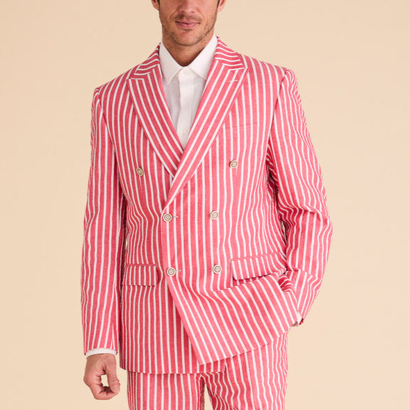 A person stands against a plain beige background, wearing the Inserch Seersucker Wide Stripe Blazer BL507-00030 in red with a crisp white shirt and brown shoes, subtly complemented by gingham check accents.
