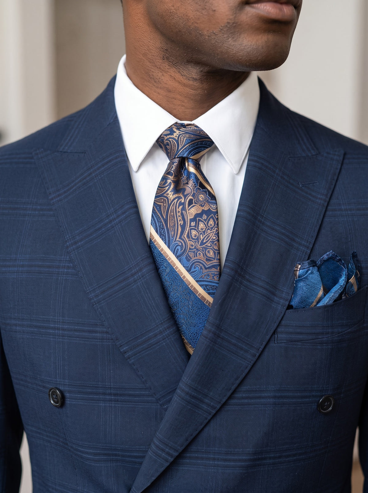 A man wearing a Tiglio Luxe PISTOIA Modern Fit Blue Plaid Double Breasted Suit WS8504 made of blue plaid Super 150′s wool, styled with a white dress shirt, patterned necktie, and matching pocket square.