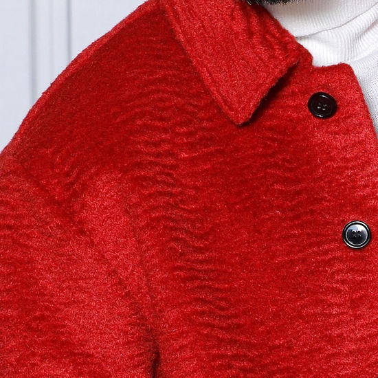 A man wearing the Insomnia "MANZINI CANADA" Red Short Ripple Faux Fur Button Coat over a white turtleneck stands against a white decorative wall.