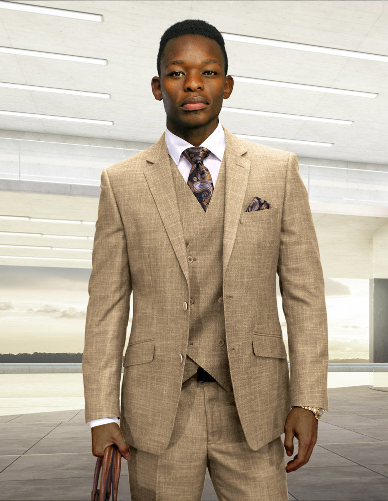 A man stands indoors in a well-lit, modern space wearing the STATEMENT CLOTHING | CARNELI-CAMEL three-piece suit from Statement Clothing, styled with a patterned tie.