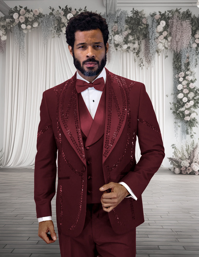 A man in the STATEMENT CLOTHING | CHIC-BURGUNDY modern fit tuxedo by Statement Clothing stands in front of a white floral and drapery wedding backdrop.