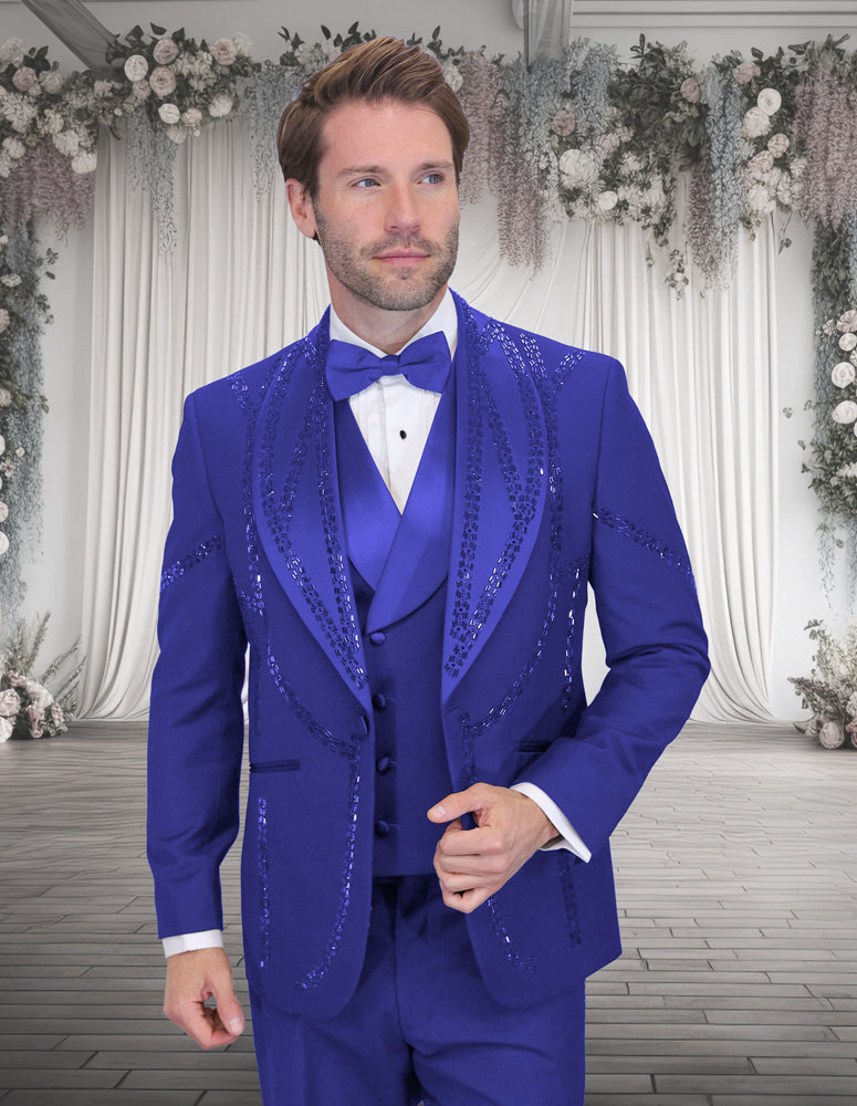 A man in the STATEMENT CLOTHING | CHIC-ROYAL royal blue tuxedo with sequins, matching vest, and bow tie by Statement Clothing poses in a floral event space, highlighting the modern fit’s elegance.