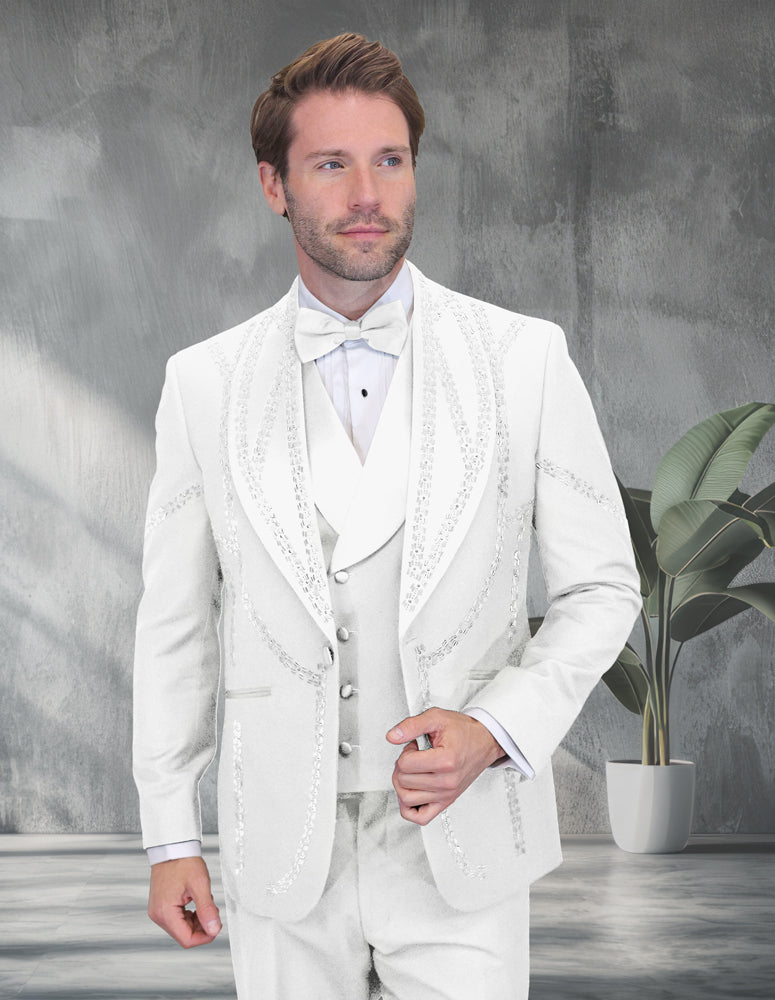 A man wears the STATEMENT CLOTHING | CHIC-WHITE modern fit white tuxedo with sequin details by Statement Clothing, standing indoors near a potted plant and gazing to the side.
