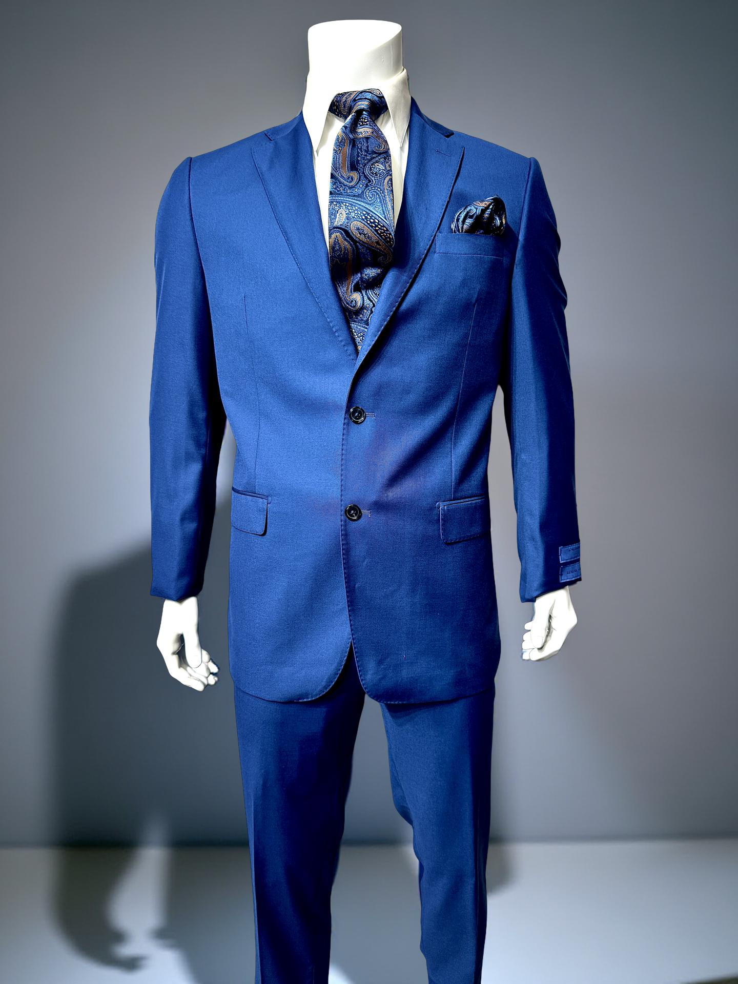 A mannequin wears the Cavellini Uomo Dolcetto MODERN FIT Suit 6667/121 by CAVELLI in royal blue, styled with a white shirt, paisley tie, and matching pocket square against a plain backdrop.