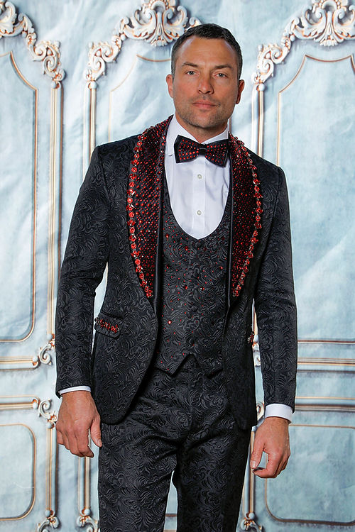 A man in an Insomnia MANZINI ENZO 3-piece slim fit black/red suit with rhinestone trim, red embellishments, bow tie, and white shirt stands against an ornate backdrop.