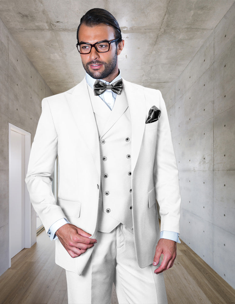 A man in the STATEMENT CLOTHING | FLORENCE-WHITE three-piece suit by Statement Clothing, wearing glasses and a bow tie, stands in a modern hallway with concrete walls and wooden floors.