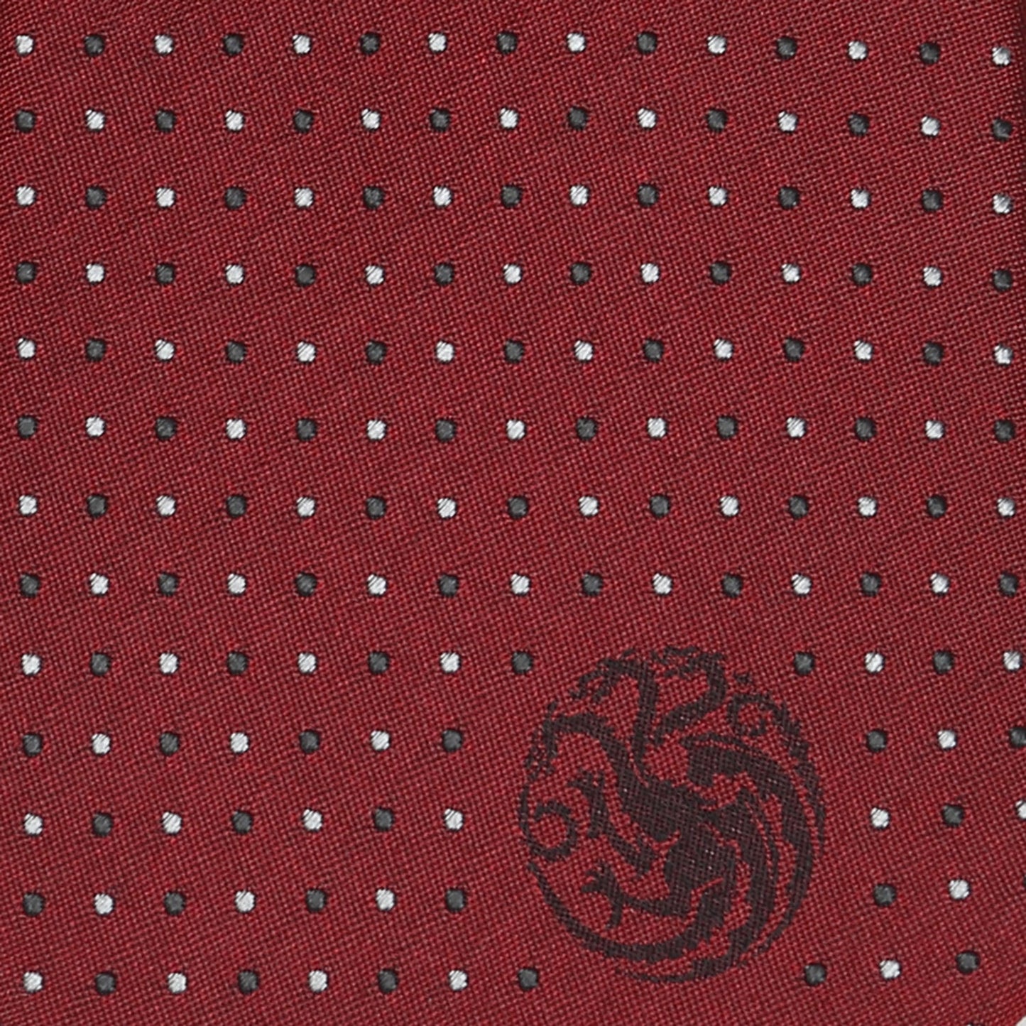 The Game of Thrones Targaryen Dragon Sigil Men's Tie by Cufflinks.com is a rolled-up red tie featuring small white polka dots and a black dragon emblem on the front.