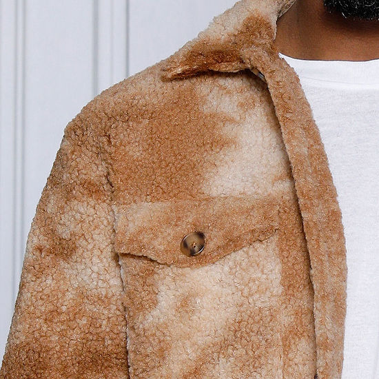 A man in a MANZINI ICELAND Brown Soft Fleece Button Sweater Shirt by Insomnia stands against a light gray background, accentuating his style with the crisp white t-shirt beneath.