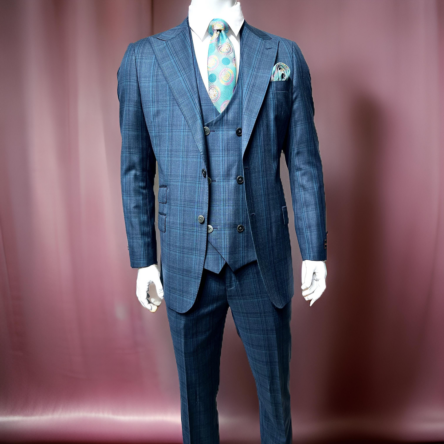 An older man wears the Tiglio Luxe Prosecco Modern Fit pure wool suit & vest in blue/teal plaid (size 54L only), paired with a white shirt and patterned tie, standing against a plain light background with a neutral expression.