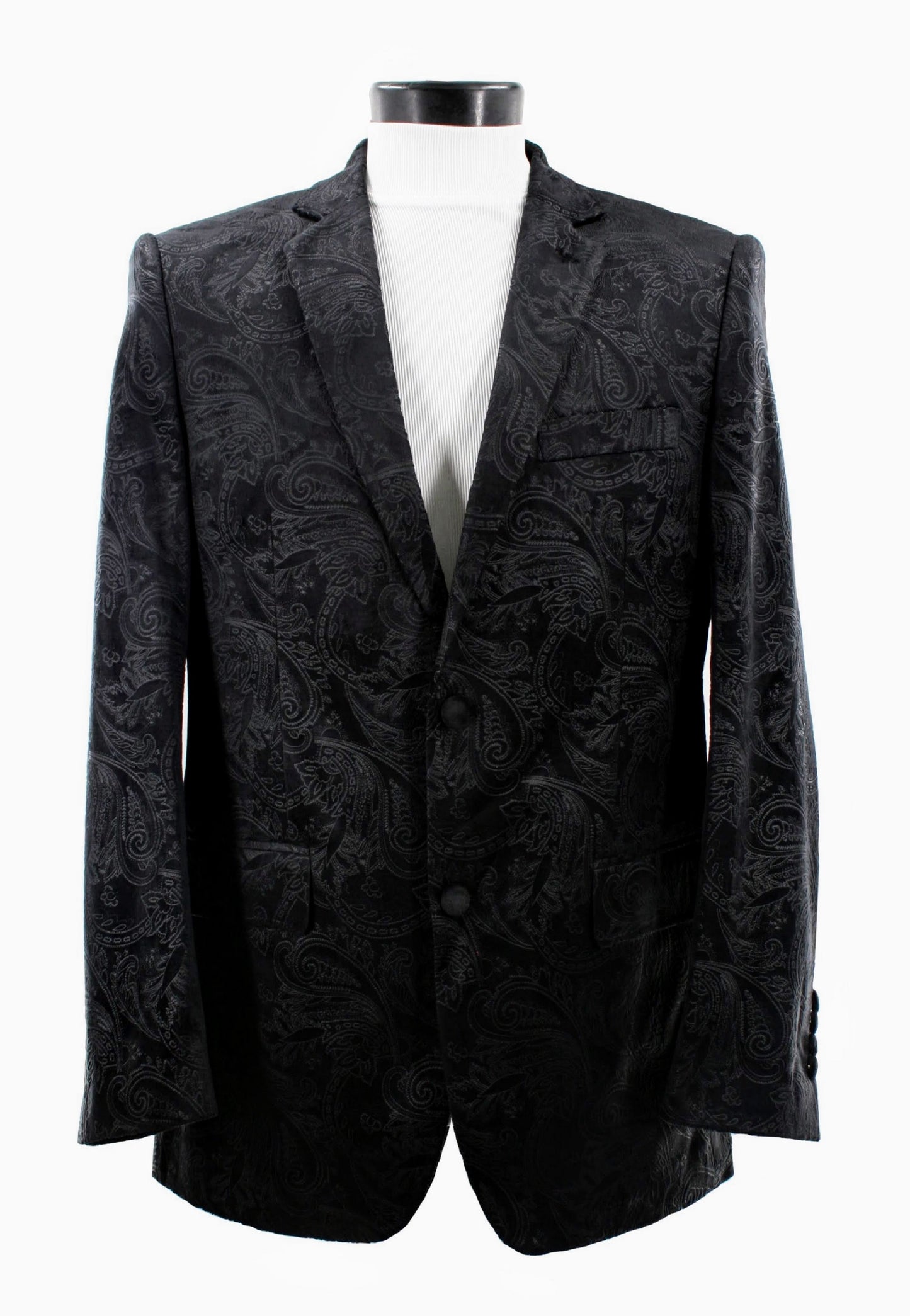 The Bassiri Blazer J1044-Black by Bassiri is displayed on a white mannequin, featuring a bold black paisley design. It elegantly complements a crisp white ribbed shirt against a plain backdrop, showcasing its timeless style.