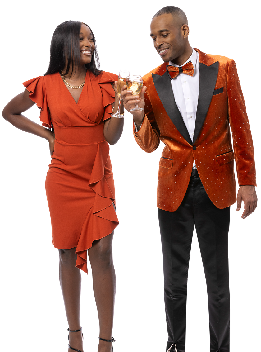 A woman in a ruffled orange dress and a man in the EJ SAMUEL Rust Blazer J197 clink glasses and smile.